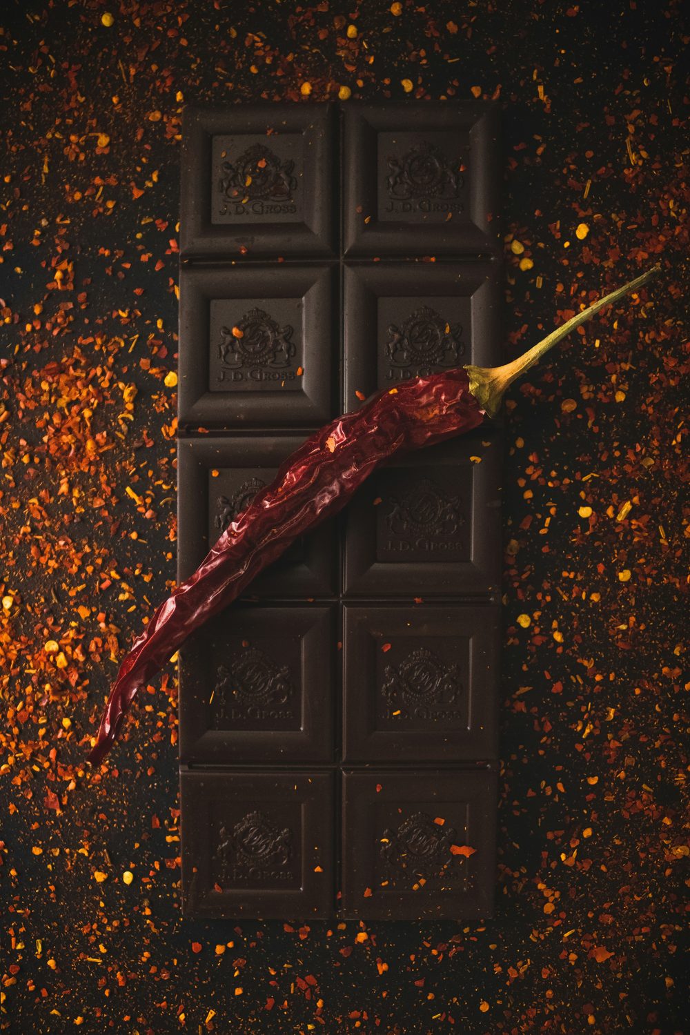 A bar of dark chocolate with a dried chilli and scattered spice